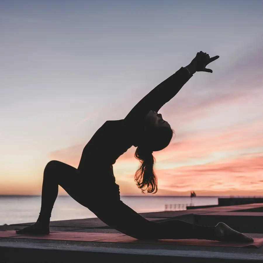 Silhouette einer Frau in einer Yoga-Haltung bei Sonnenuntergang am Meer